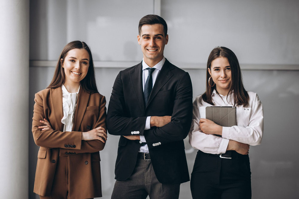 Tres ejecutivos de pie sonriendo hacia la camara